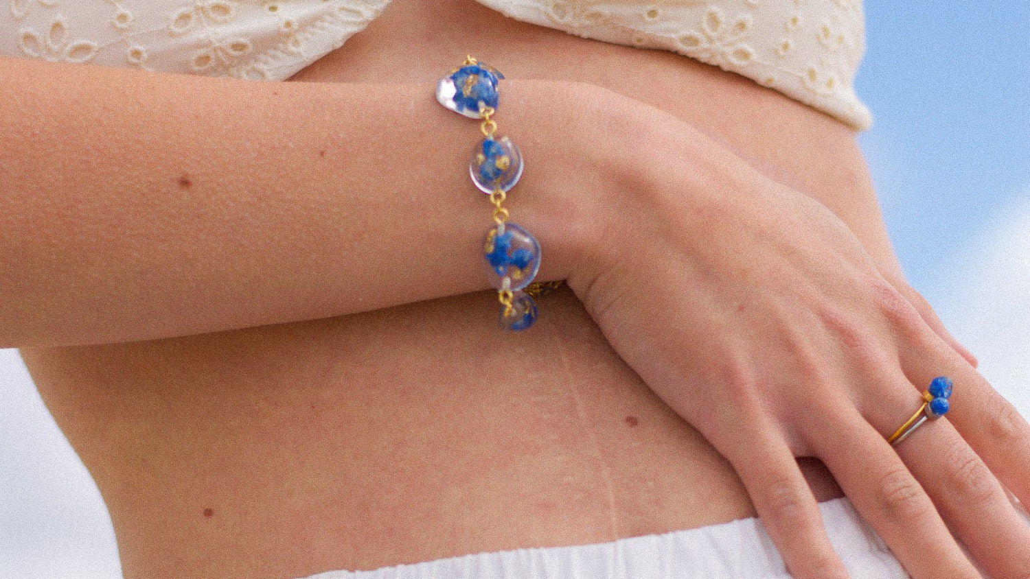 Person wearing a white strapless top and white pants with a blue sky background