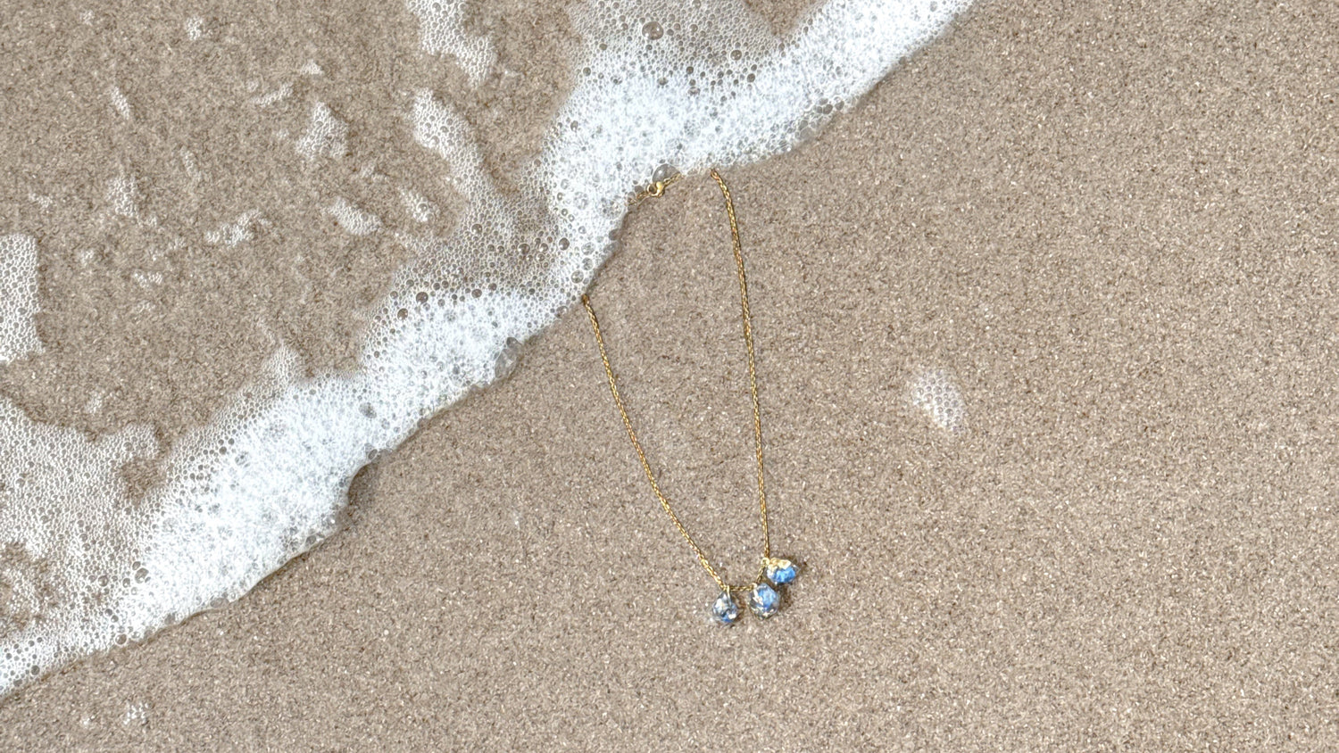Necklace with a blue pendant on sand near water