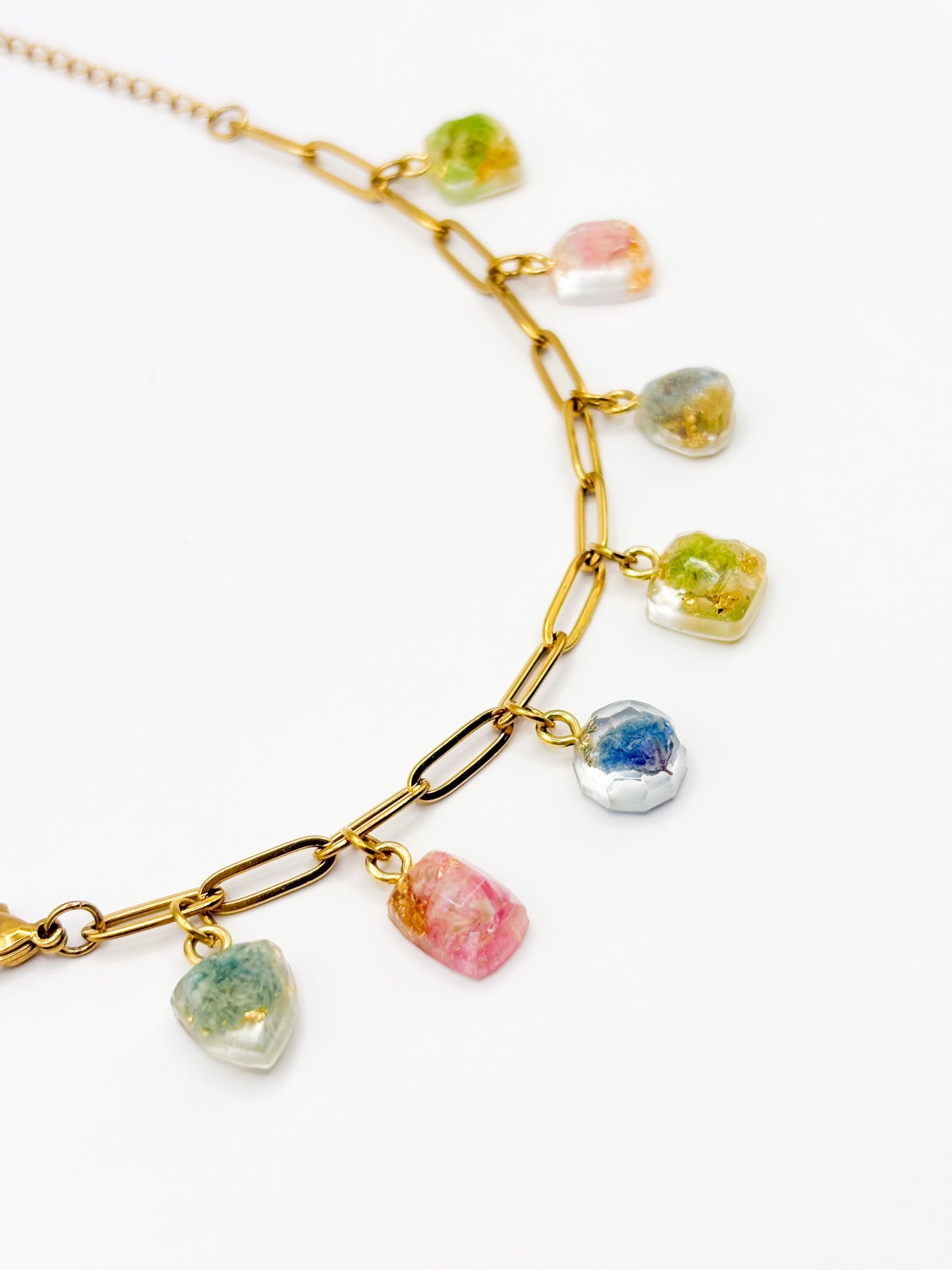Gold bracelet with colorful gemstone pendants on a white background