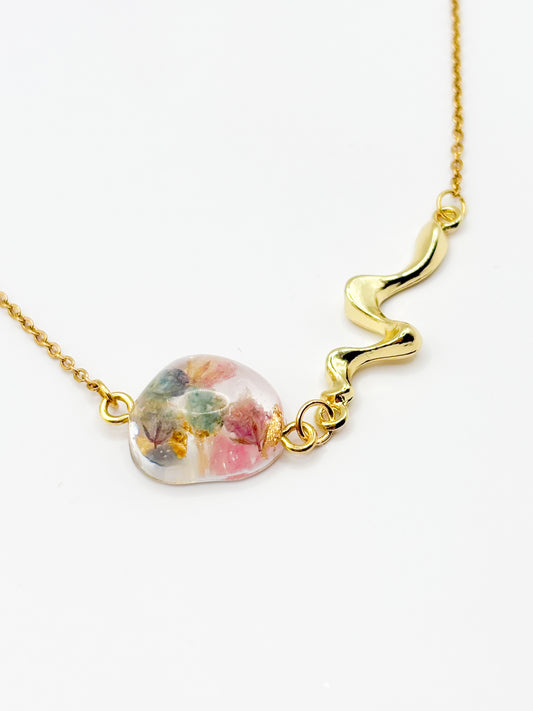 Gold necklace with a round pendant featuring colorful flowers on a white background