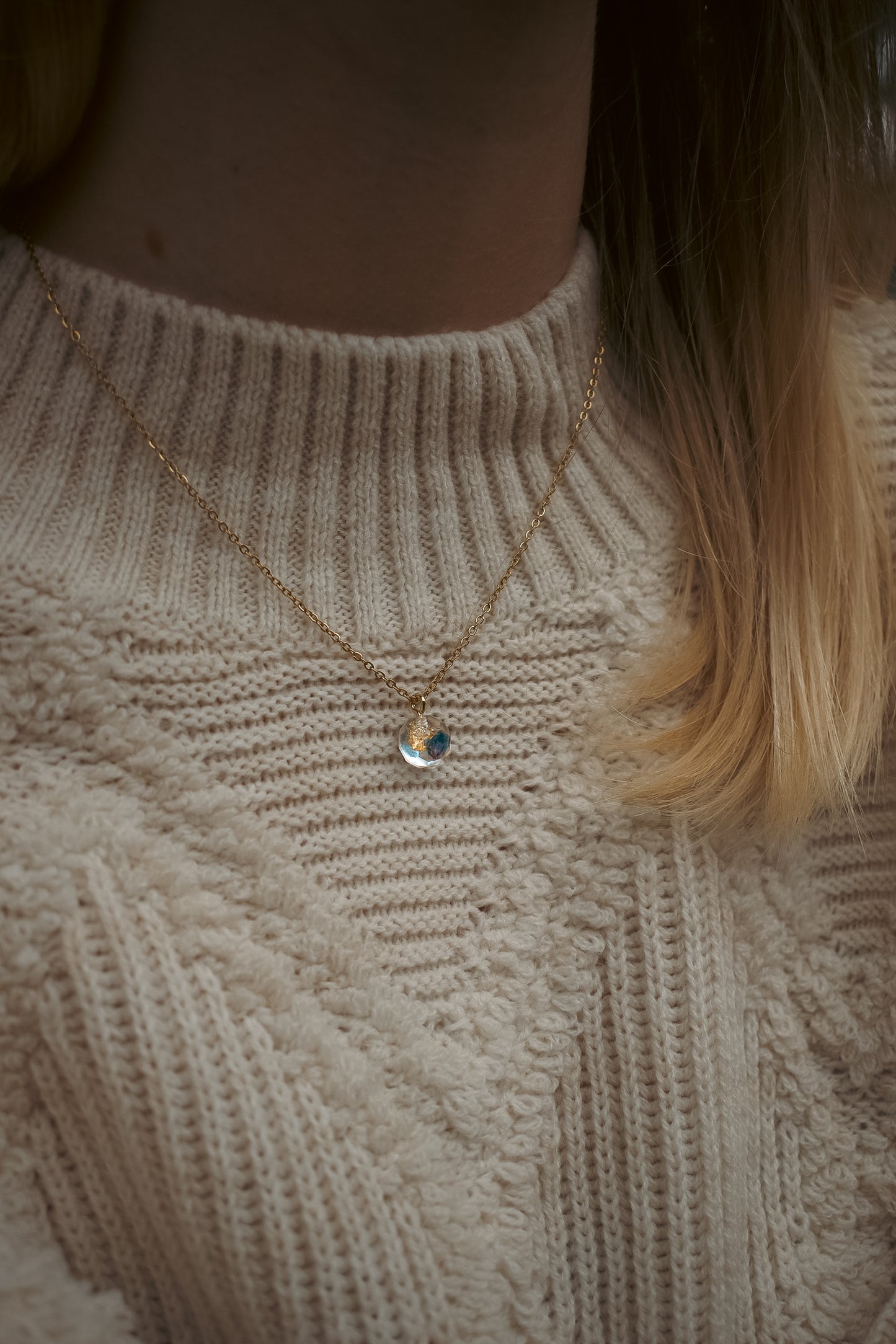 CH Design blue real flower necklace on a textured cream sweater