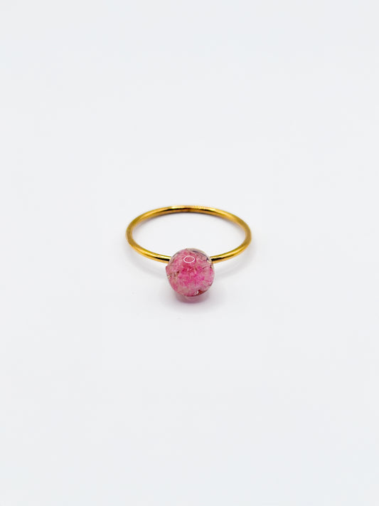Gold ring with a pink flower as gemstone on a white background