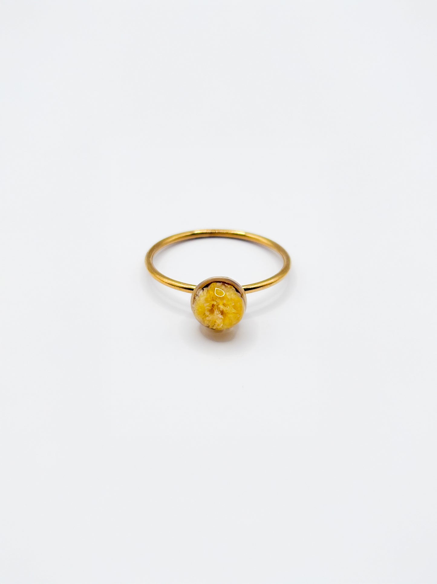 Gold ring with a yellow gemstone on a white background