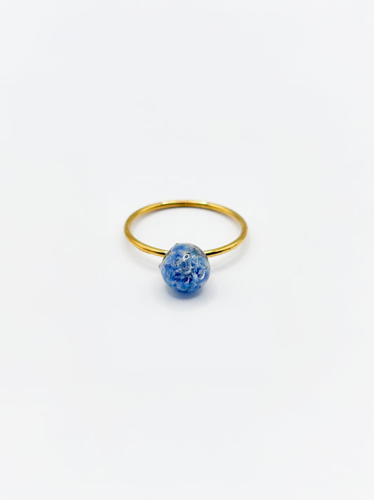 Gold ring with a blue flower on a white background