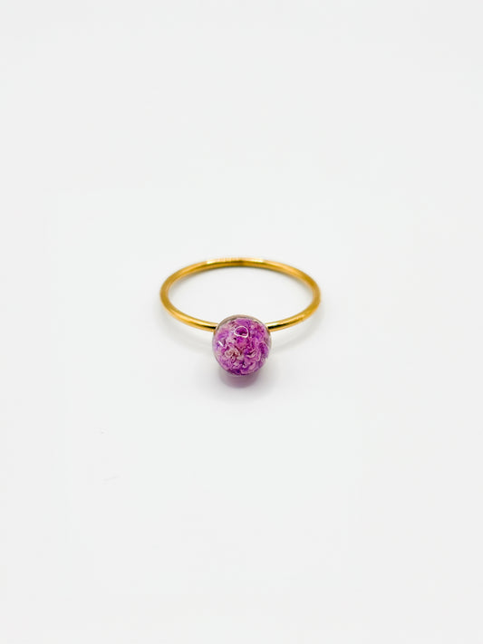 Gold ring with a purple flower on a white background
