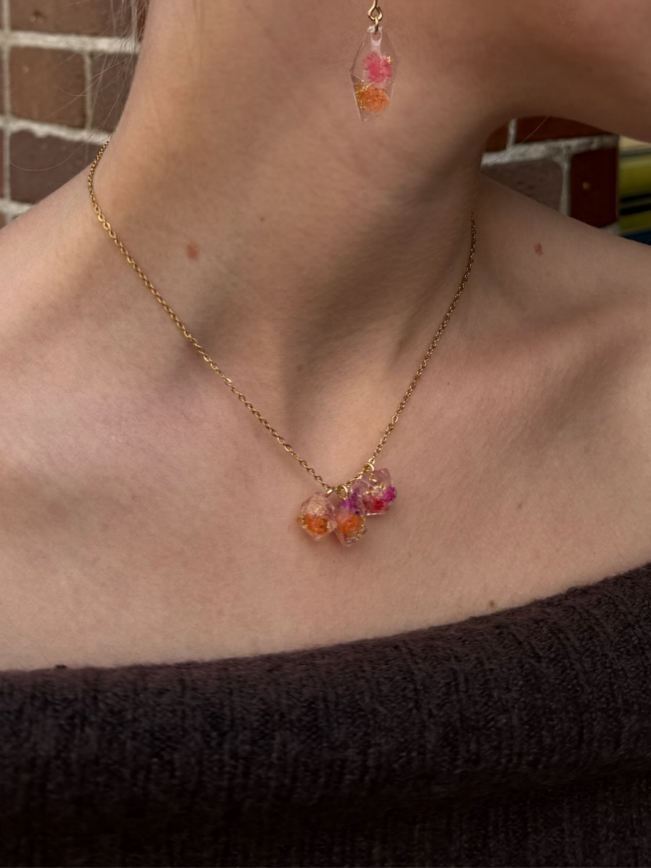 Close-up of a person wearing a necklace and earrings with a brick wall background