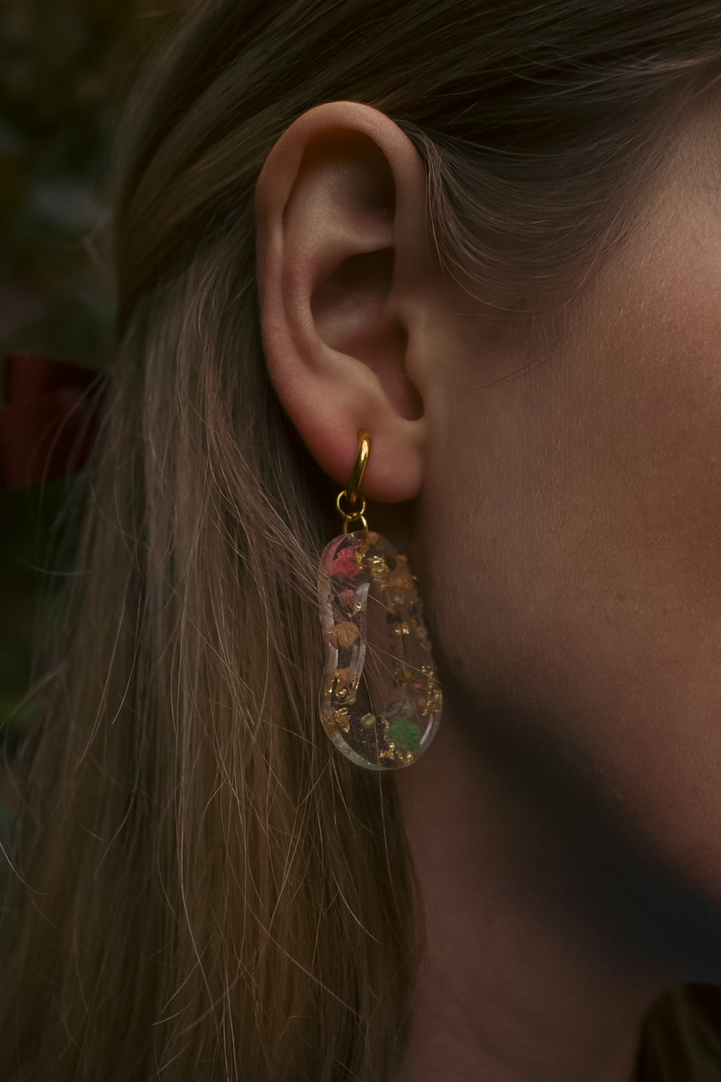Close-up of an ear wearing a floral earring with a blurred background