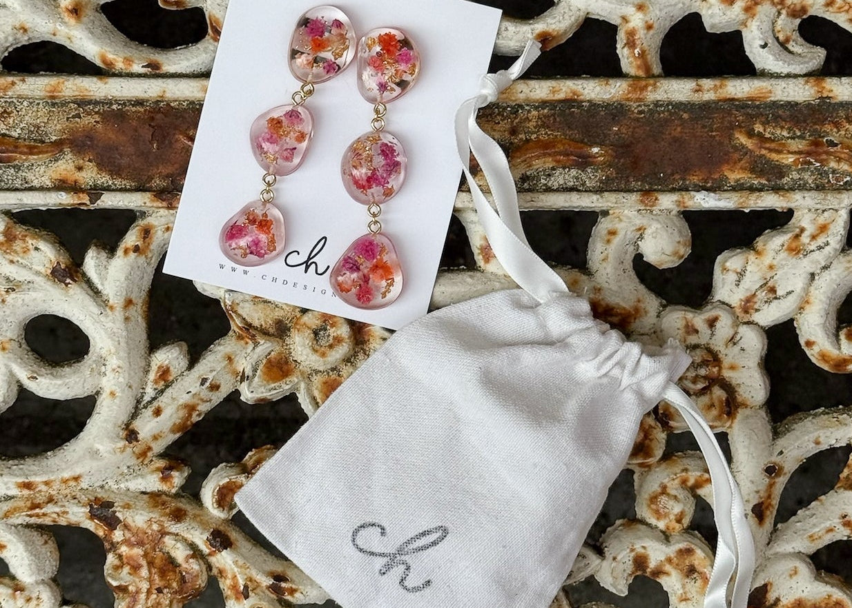 Floral earrings with a white pouch on a decorative metal surface
