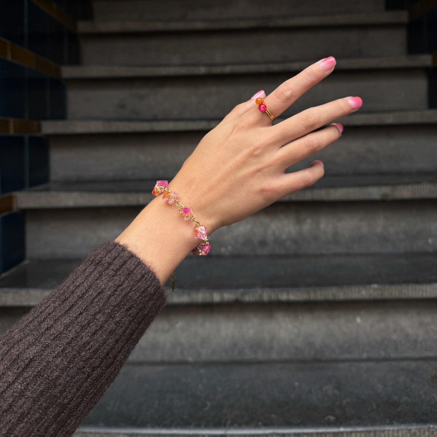 Hand wearing a bracelet with pink beads against a staircase background