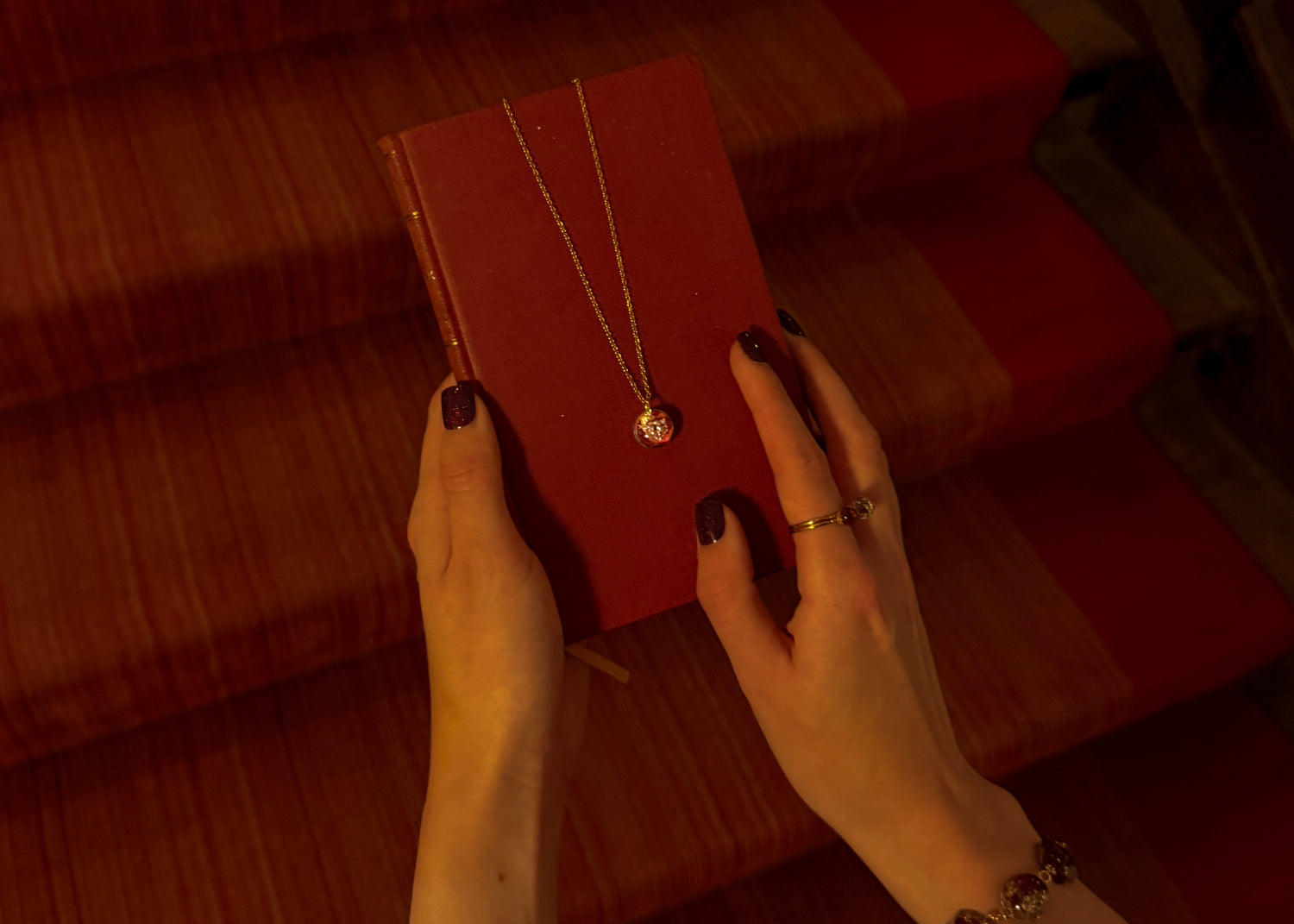 Person holding a red box with a necklace against a textured red background