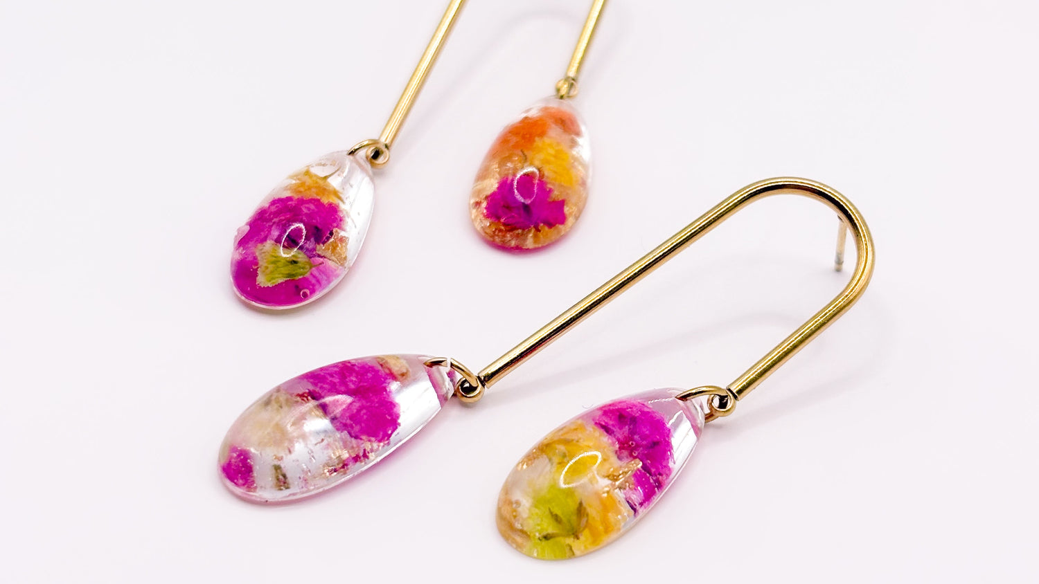 Gold teardrop earrings with floral designs on a white background
