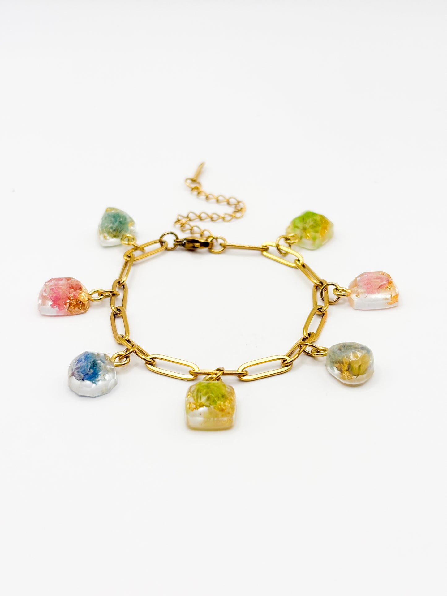 Gold bracelet with colorful gemstone charms containing real flowers on a white background