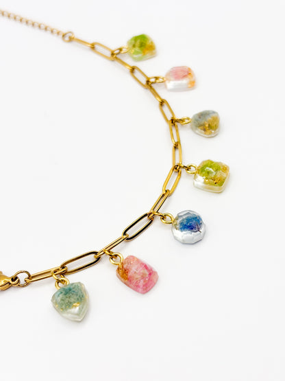 Gold bracelet with colorful gemstone pendants on a white background