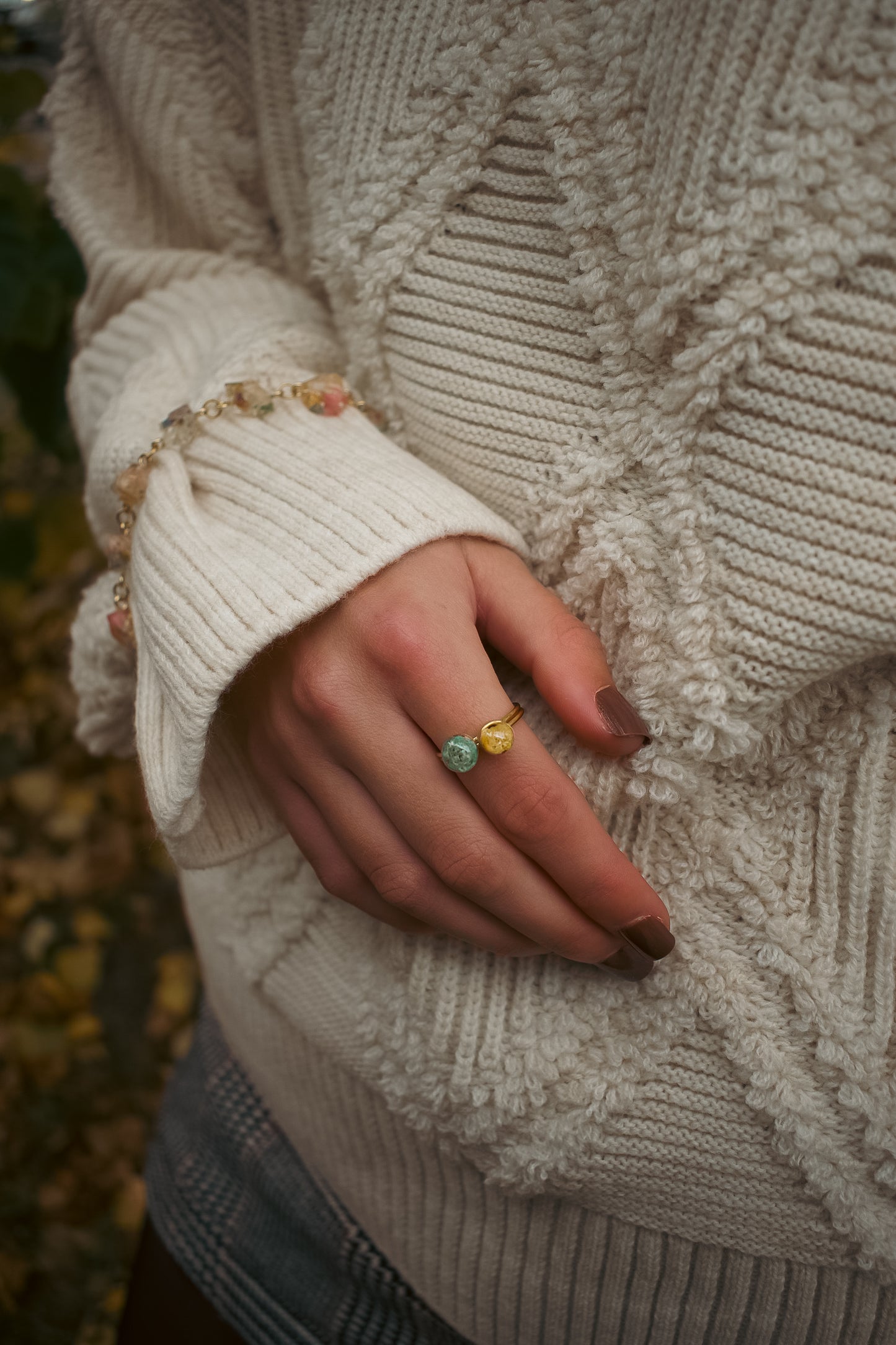 Close-up of a person wearing a textured sweater with a hand adorned with rings.