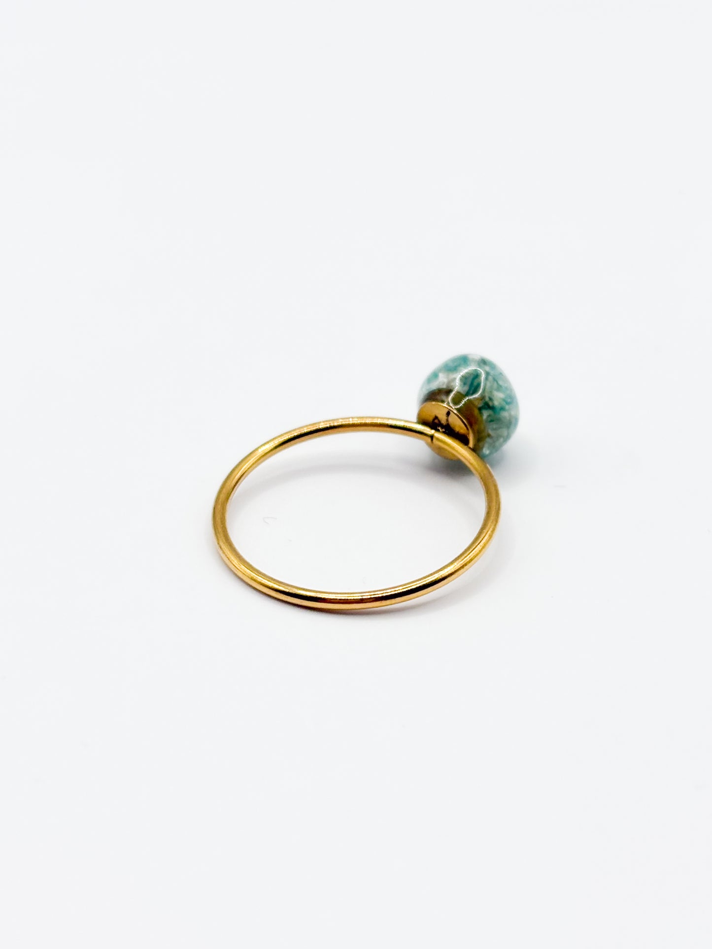 Gold ring with a green gemstone on a white background