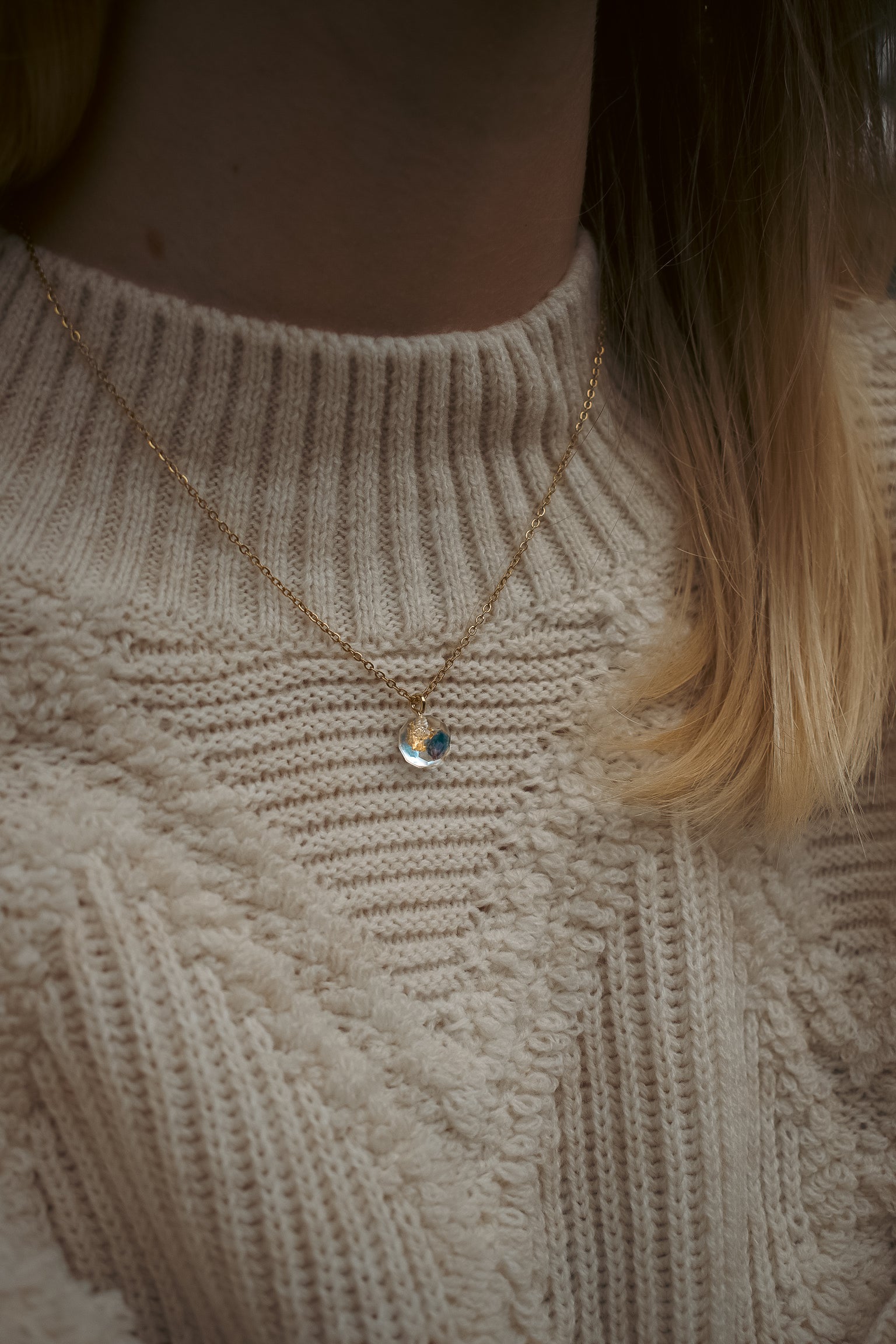 CH Design blue real flower necklace on a textured cream sweater