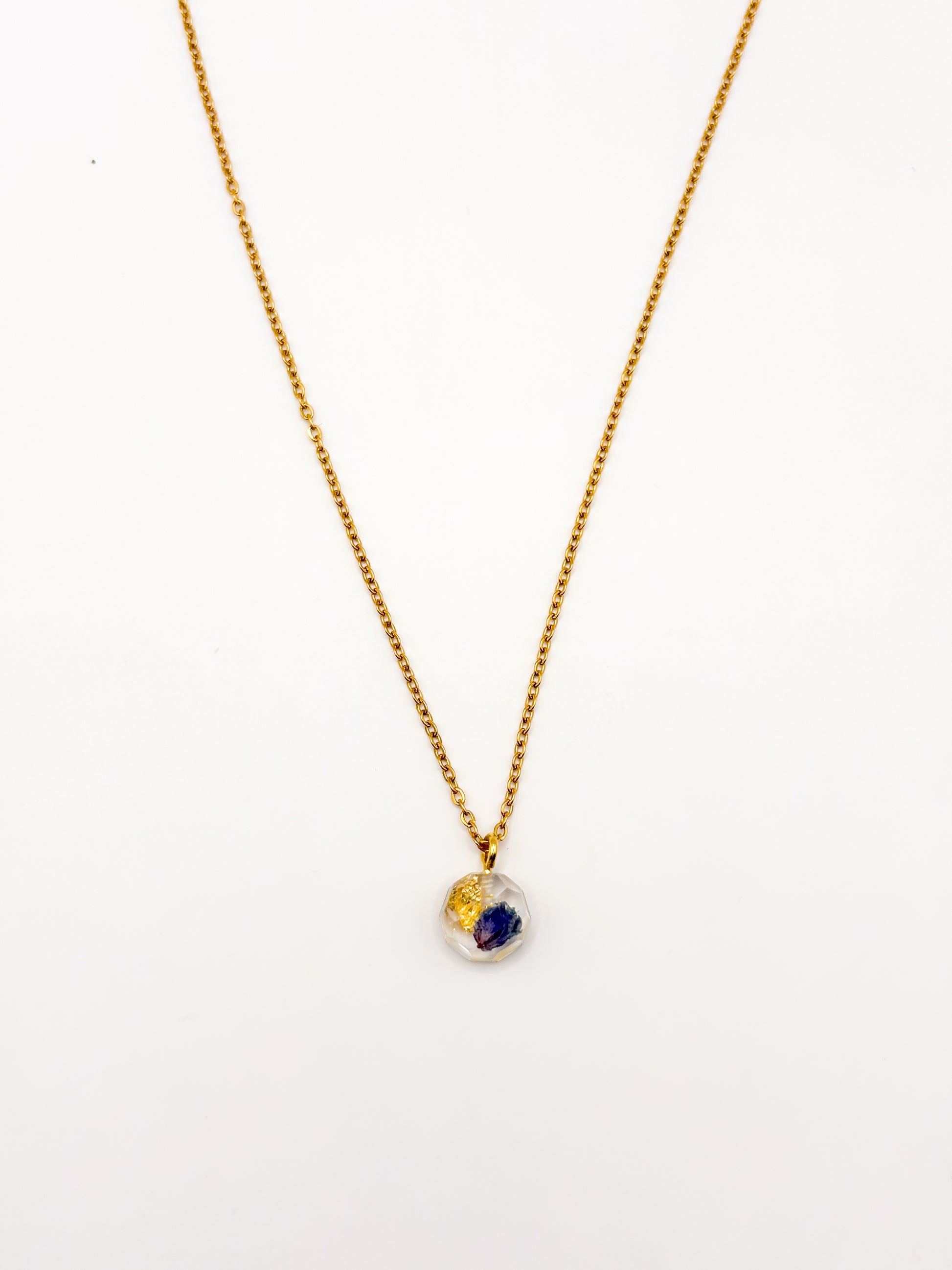Gold necklace with a small pendant on a white background
