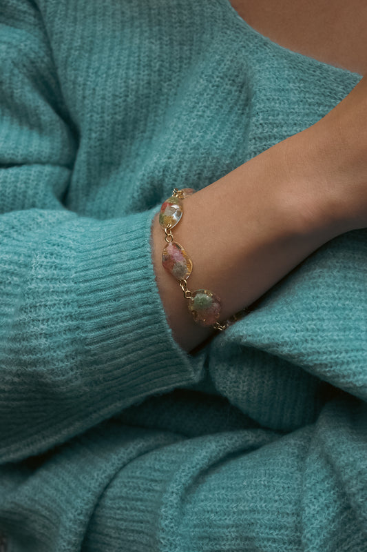 Bracelet with pendants containing real flowers on a teal sweater