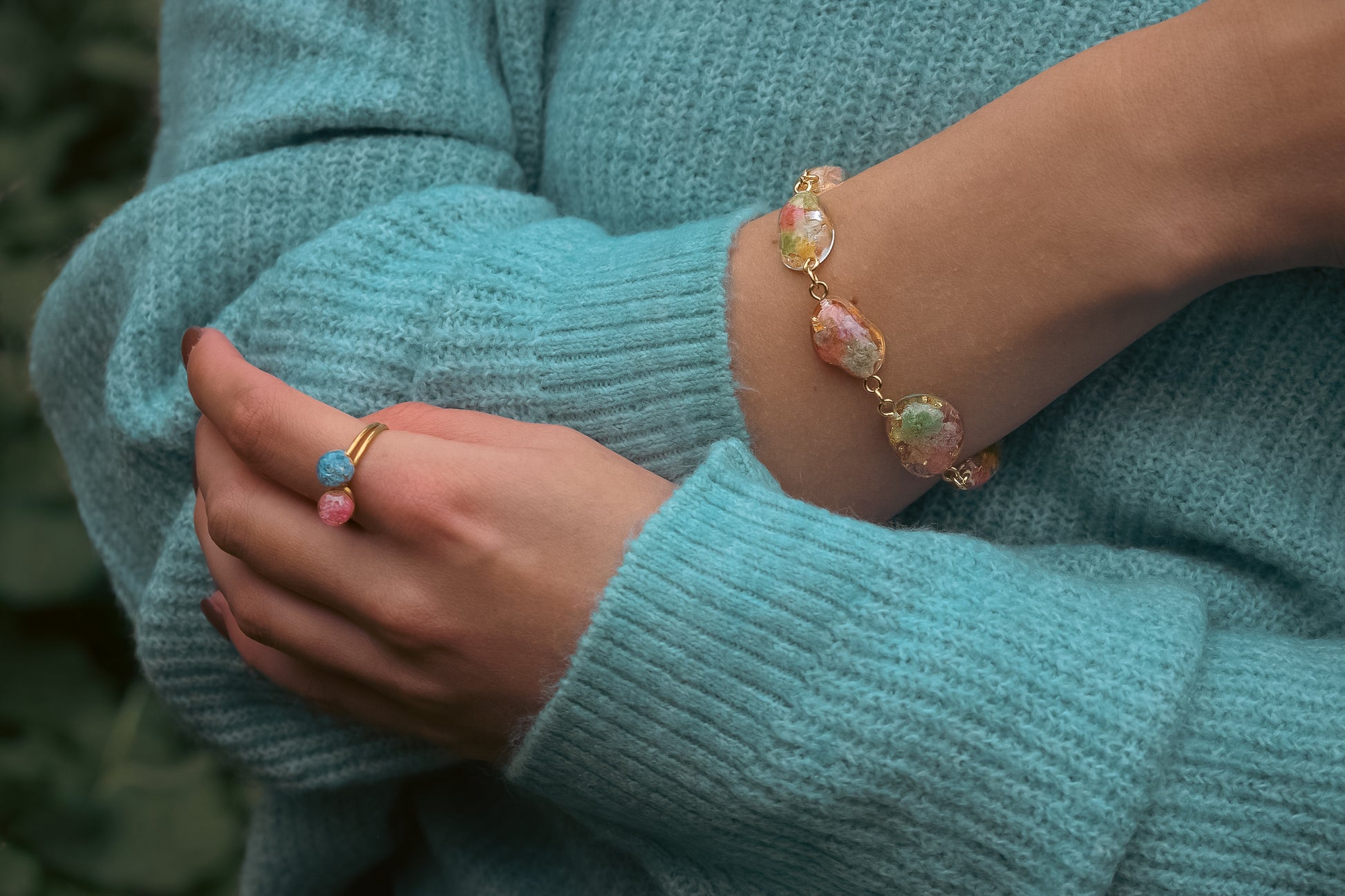 Bracelet with pendants containing real flowers on a teal sweater horizontal