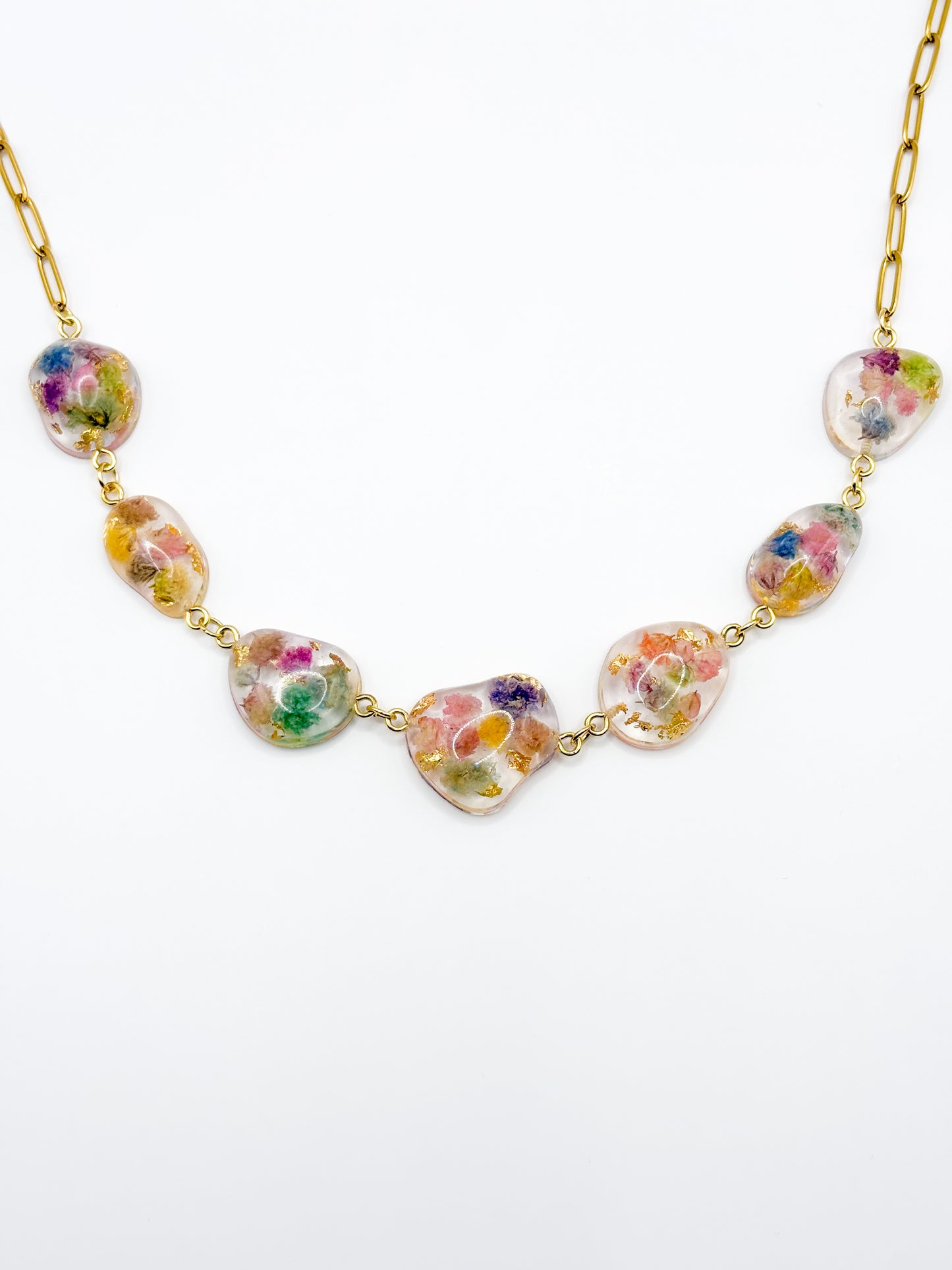 Necklace with floral heart-shaped beads on a gold chain against a white background