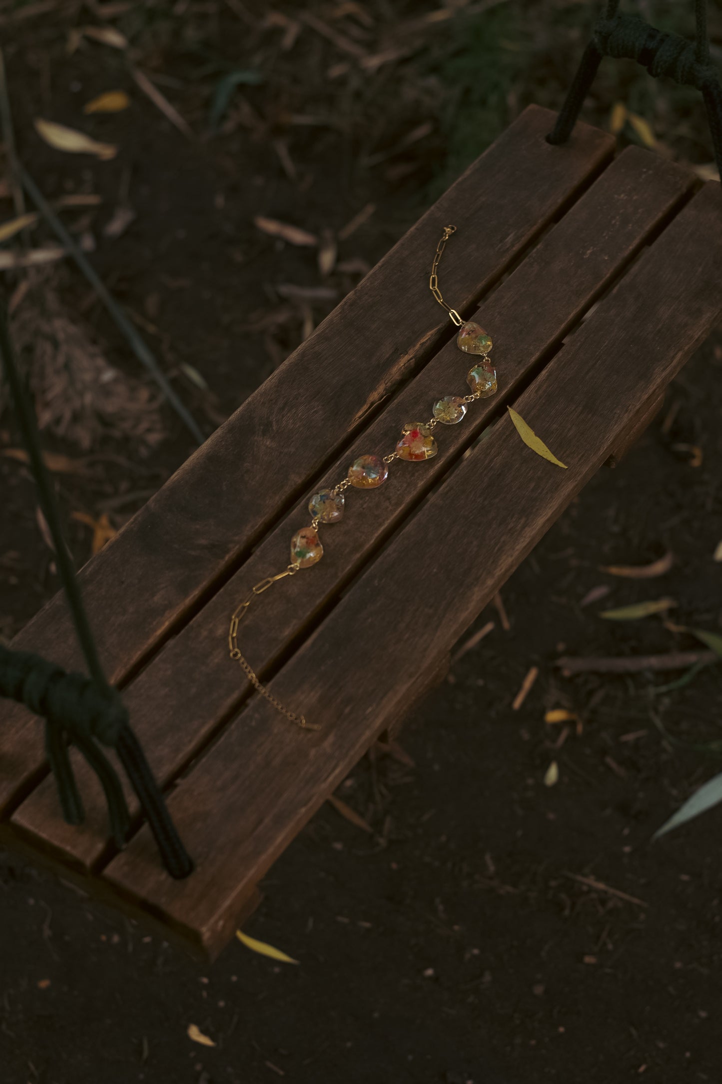 A swing with a statement necklace with pendants shaped like pebbles containing real flowers.