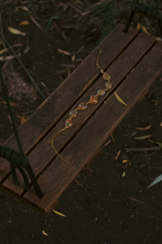 A swing with a statement necklace with pendants shaped like pebbles containing real flowers.
