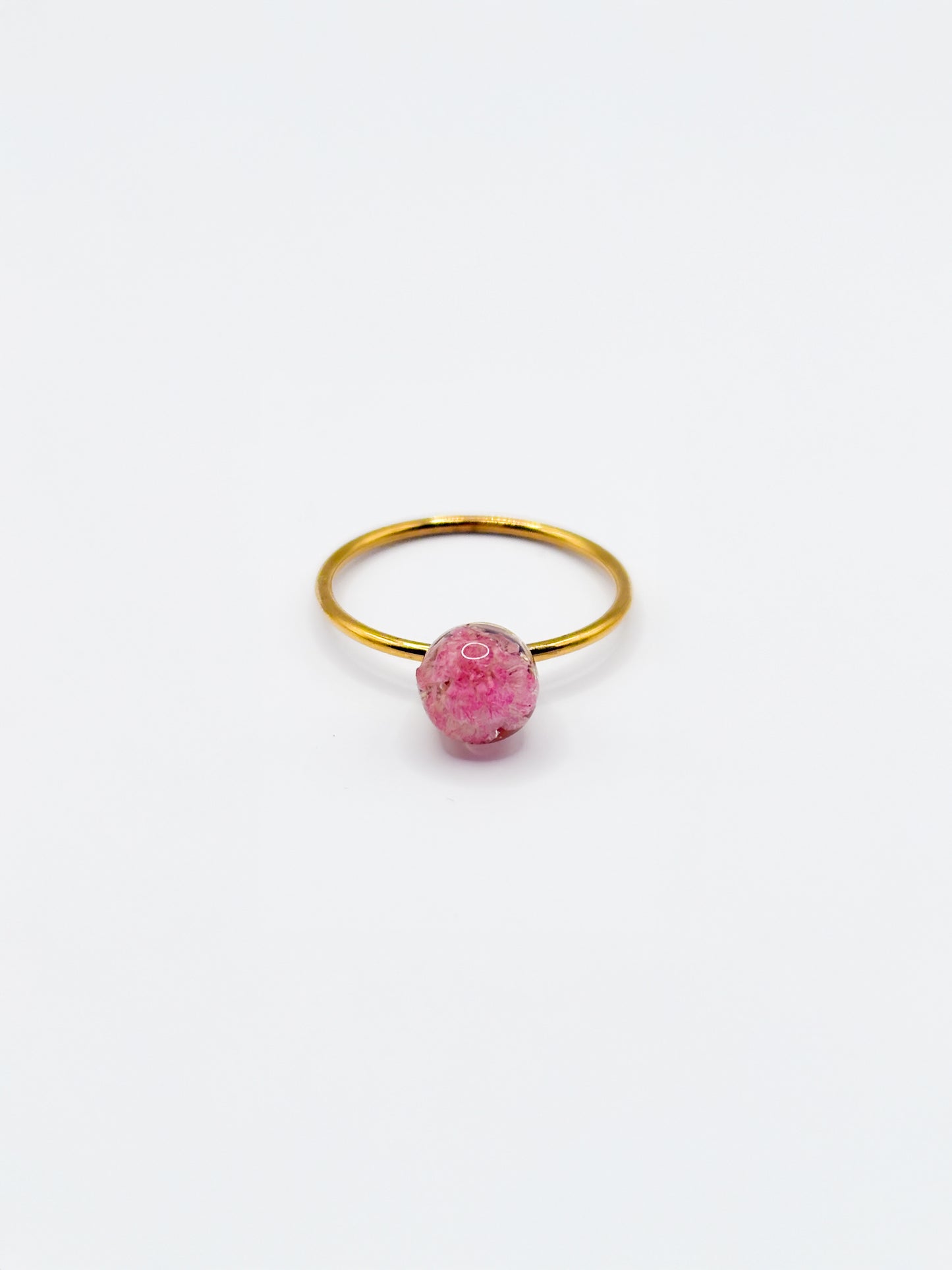 Gold ring with a pink flower as gemstone on a white background