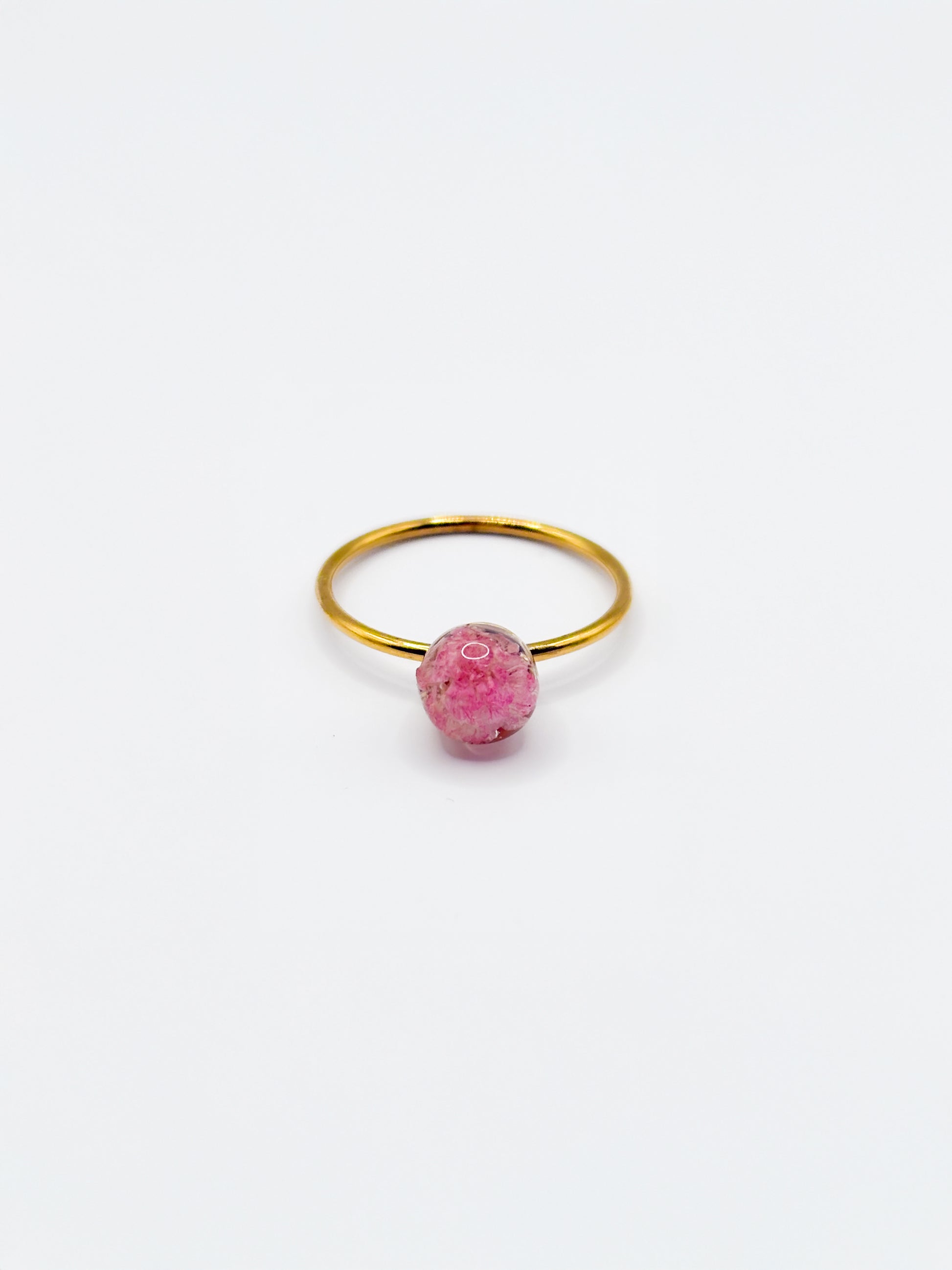 Gold ring with a pink flower as gemstone on a white background