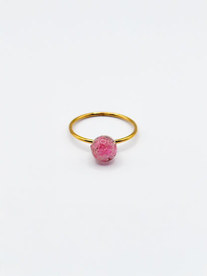 Gold ring with a pink flower as gemstone on a white background