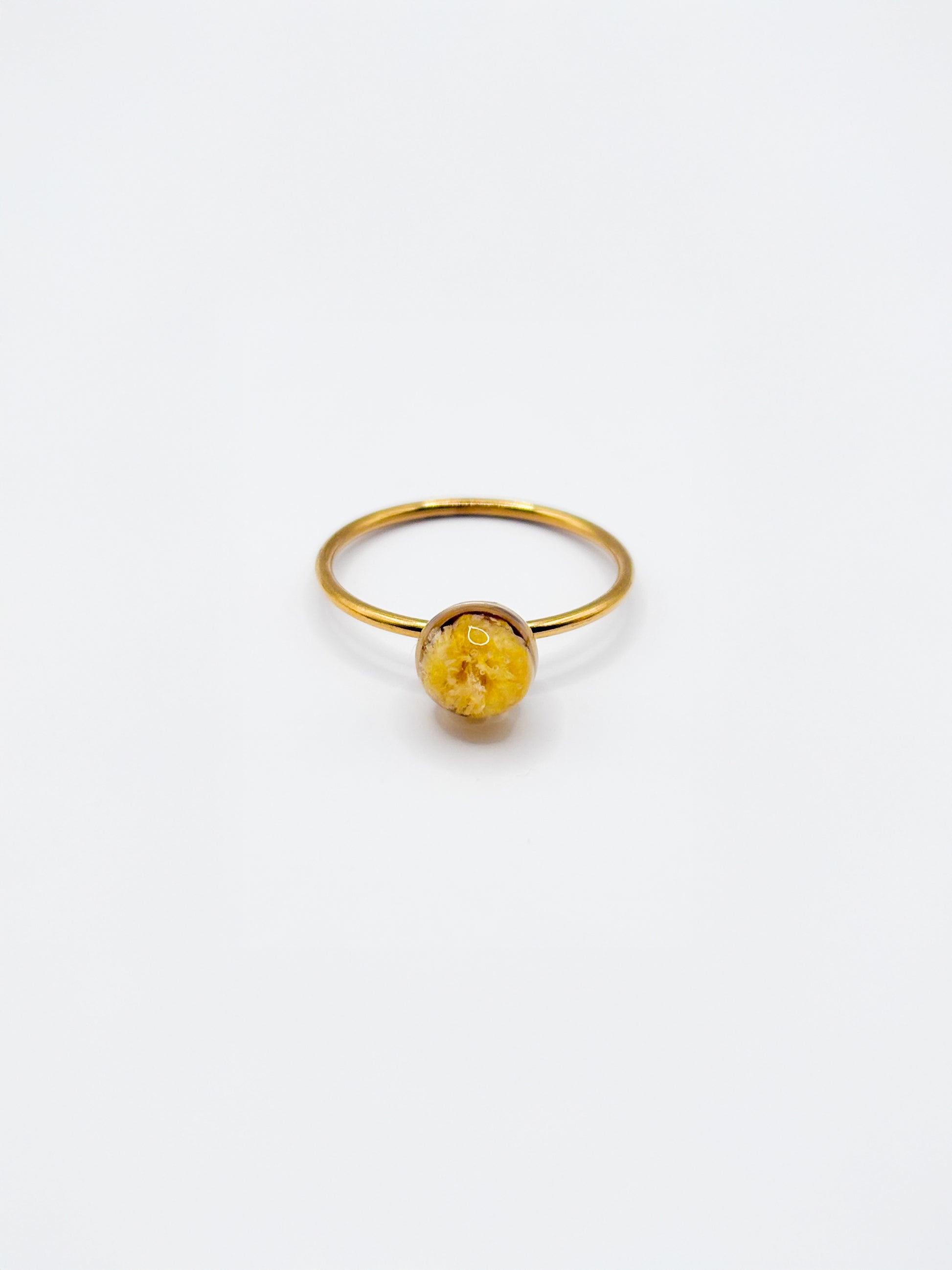 Gold ring with a yellow gemstone on a white background