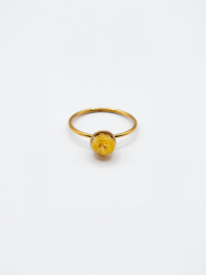 Gold ring with a yellow gemstone on a white background