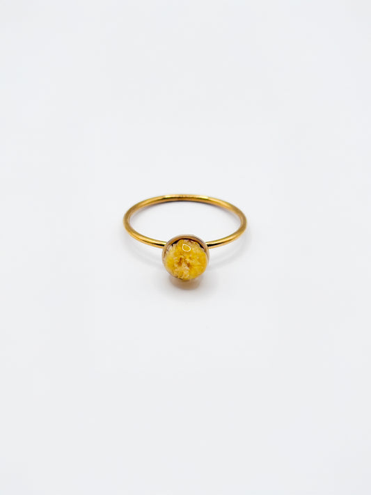 Gold ring with a yellow gemstone on a white background