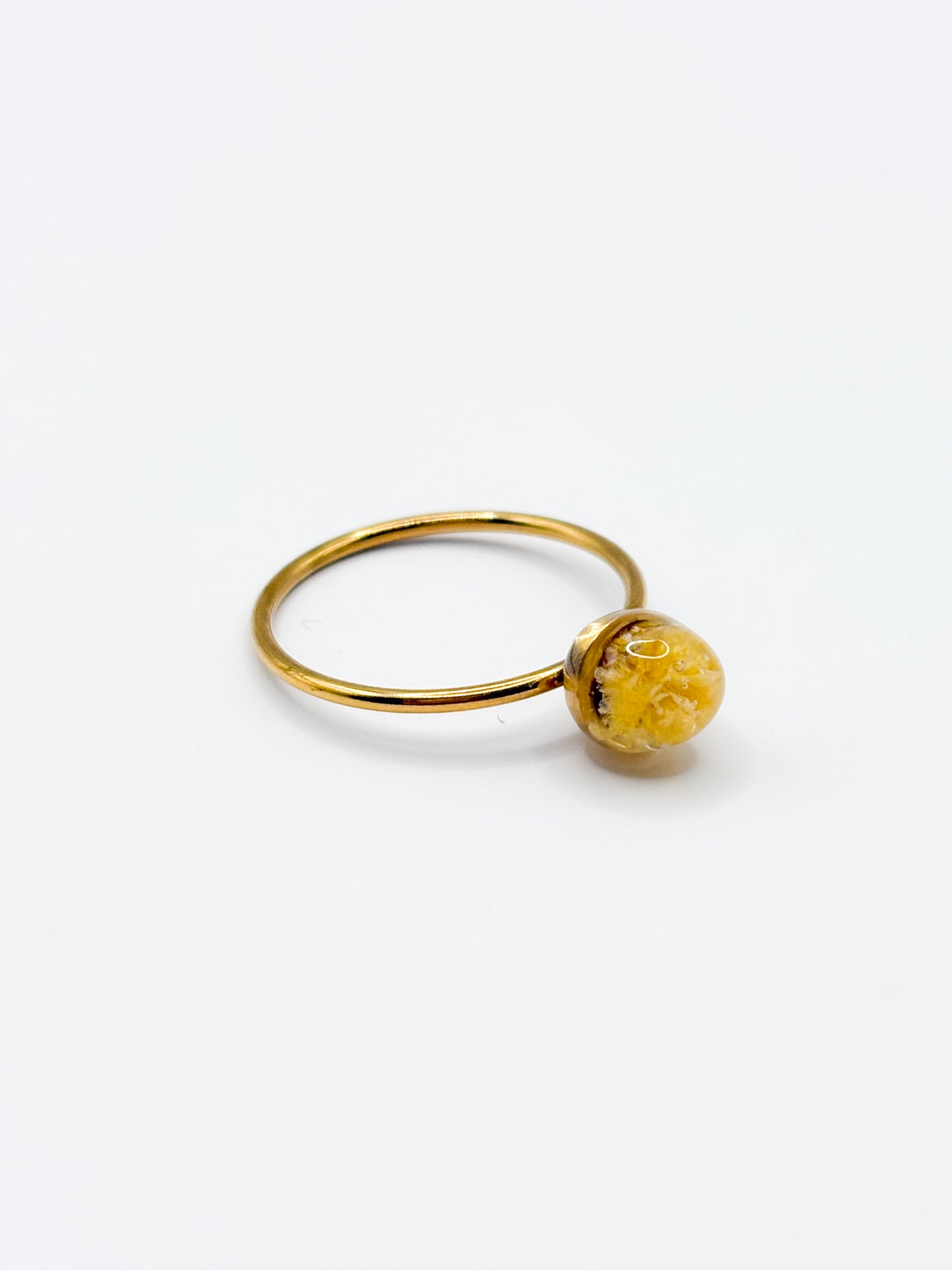 Gold ring with a yellow gemstone on a white background