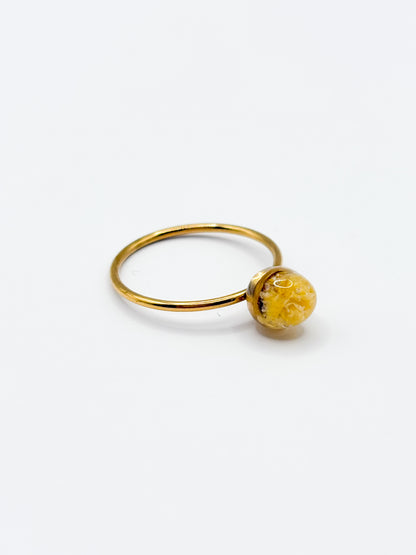 Gold ring with a yellow gemstone on a white background