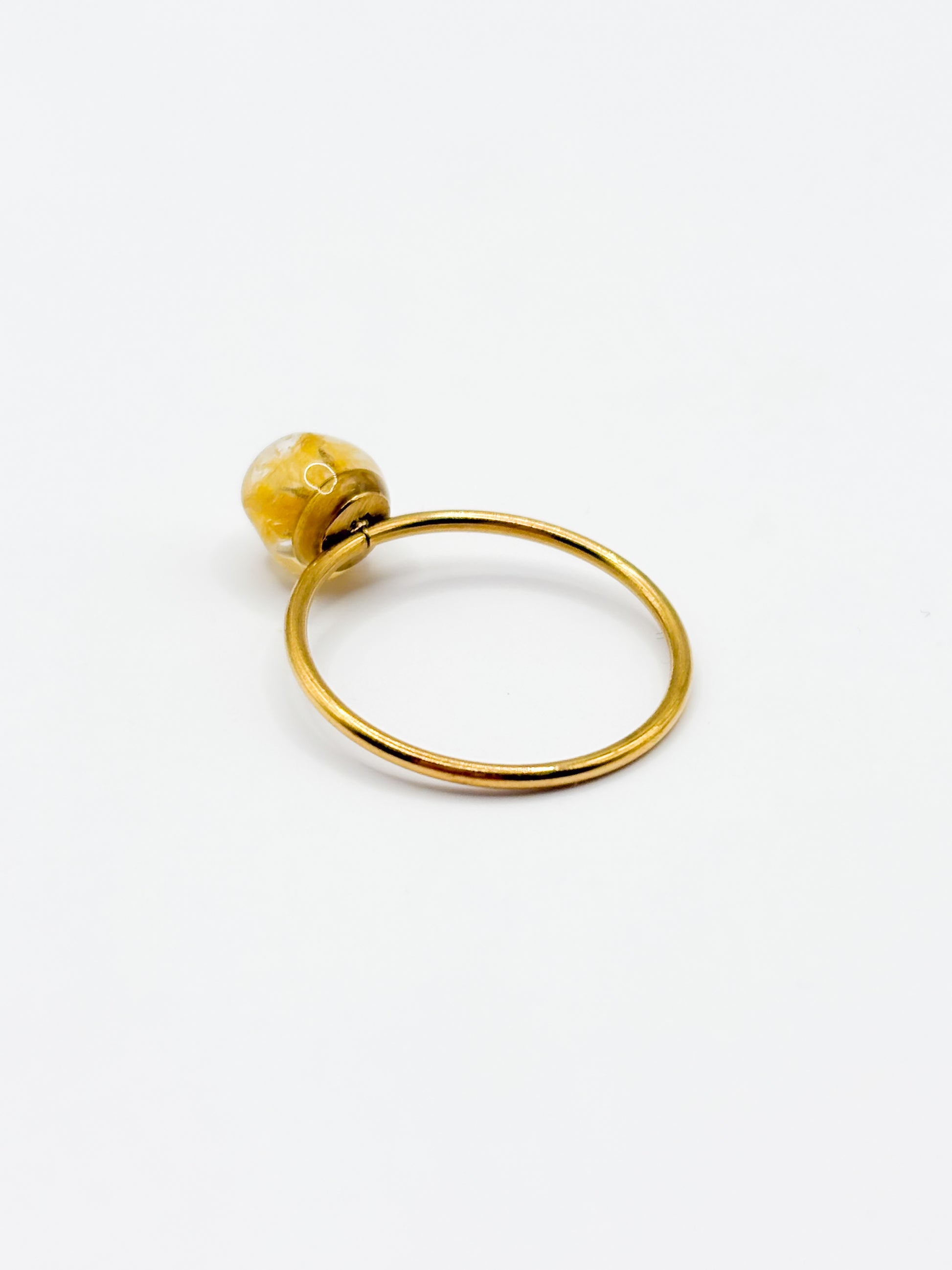 Gold ring with a yellow gemstone on a white background
