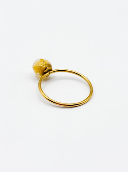 Gold ring with a yellow gemstone on a white background