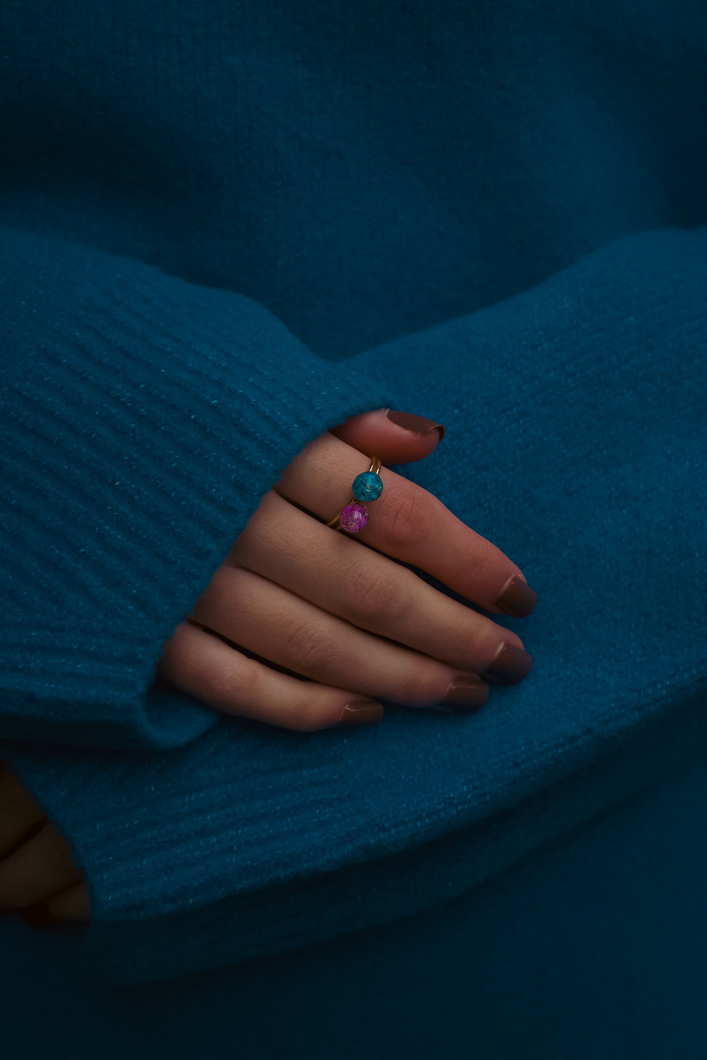 Hand with 2 real flower rings wearing a blue sweater
