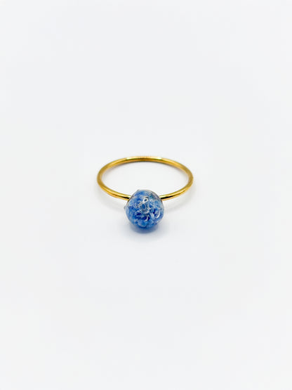 Gold ring with a blue flower on a white background