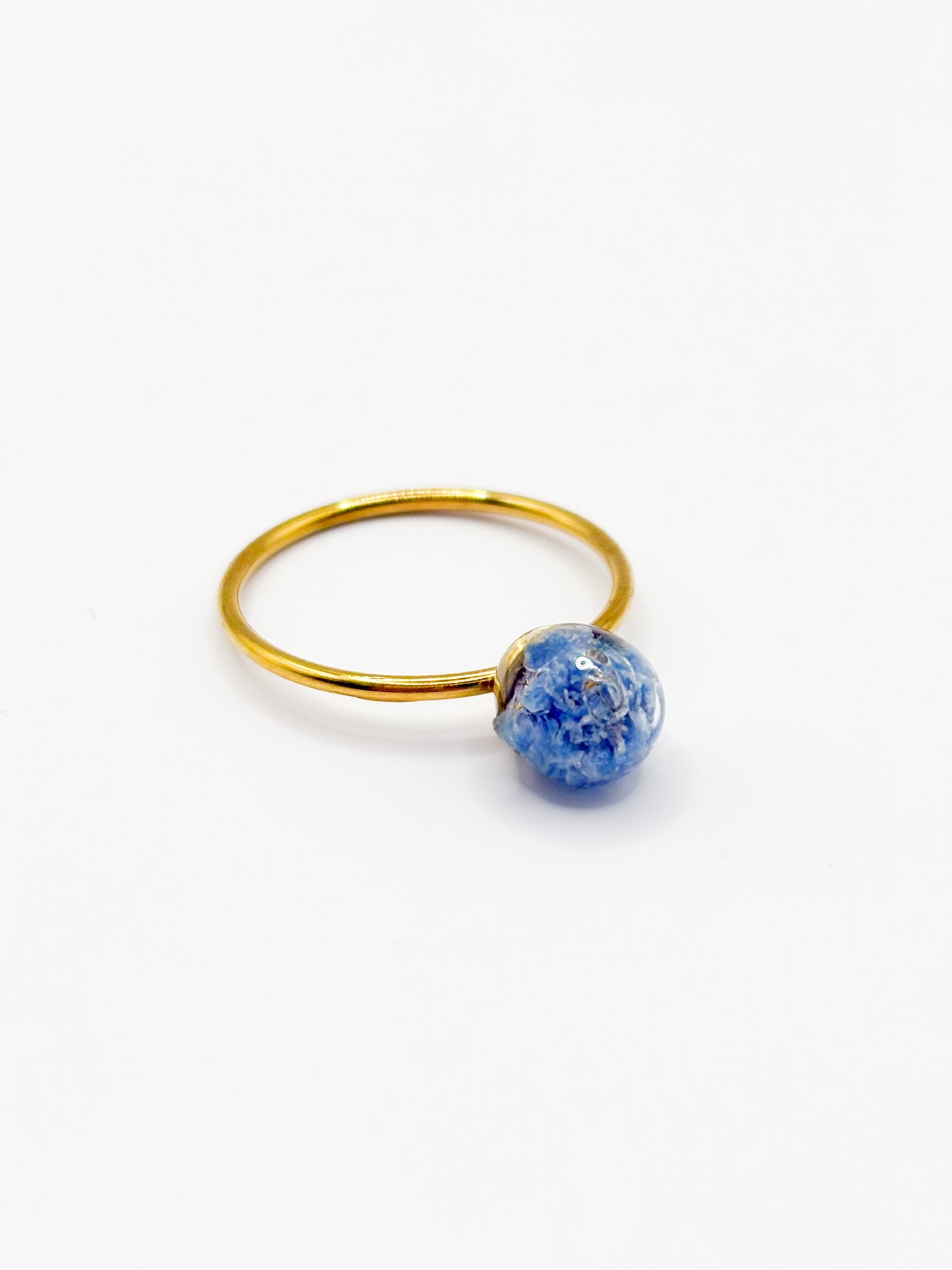 Gold ring with a blue flower gemstone on a white background