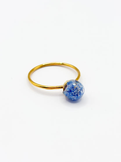 Gold ring with a blue flower gemstone on a white background