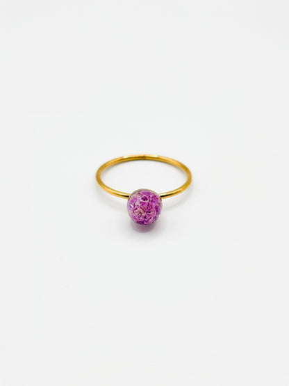 Gold ring with a purple flower on a white background